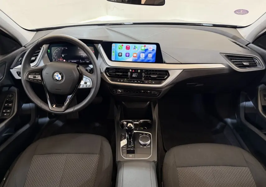 Vue intérieure avant de la BMW Série 1 116i Business Design avec tableau de bord numérique et écran tactile central.