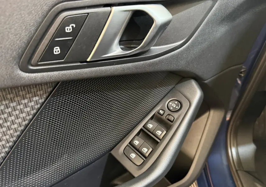 Gros plan sur la porte avant gauche bleu d'une BMW Série 1 116i, montrant les commandes des vitres et la poignée intérieure.