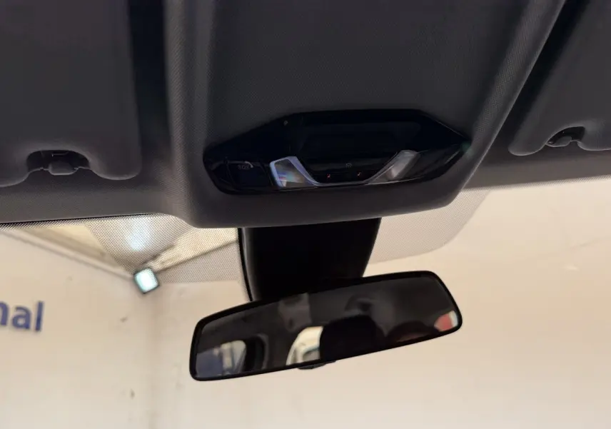 Vue intérieure centrée sur le rétroviseur et la console de plafonnier d’une BMW Série 1 116i 2023.