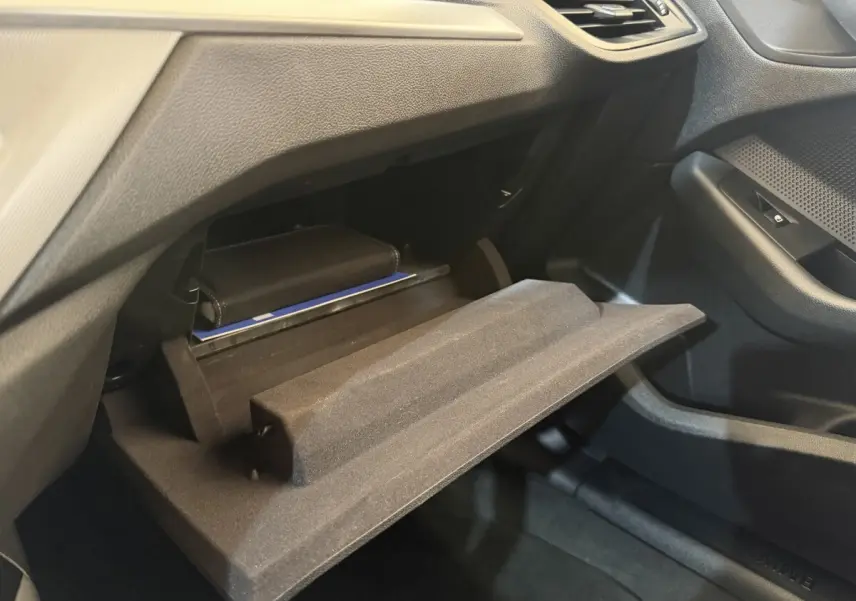 Vue intérieure côté passager de la BMW Série 1 116i Business Design 2023 avec boîte à gants ouverte et rangement visible.