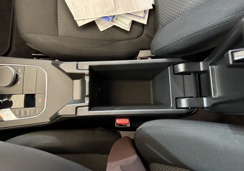 Vue plongeante sur la console centrale noire et les sièges tissu gris foncé de la BMW Série 1 116i 2023.