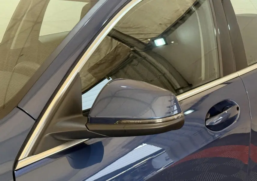 Gros plan sur le rétroviseur côté gauche bleu métallisé de la BMW Série 1 116i Business Design 2023.