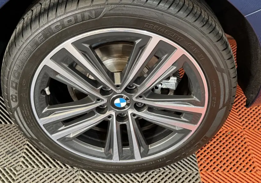 Gros plan sur la roue avant droite de la BMW Série 1 116i Business Design bleu, avec jante alliage à multiples branches.