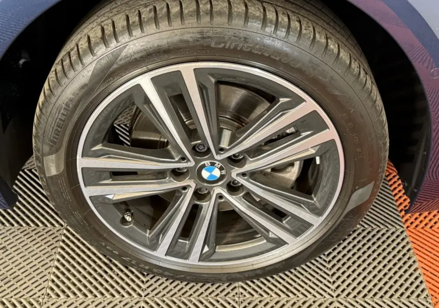 Gros plan sur la jante alliage grise et noire d'une BMW Série 1 116i Business Design bleu, côté droit.