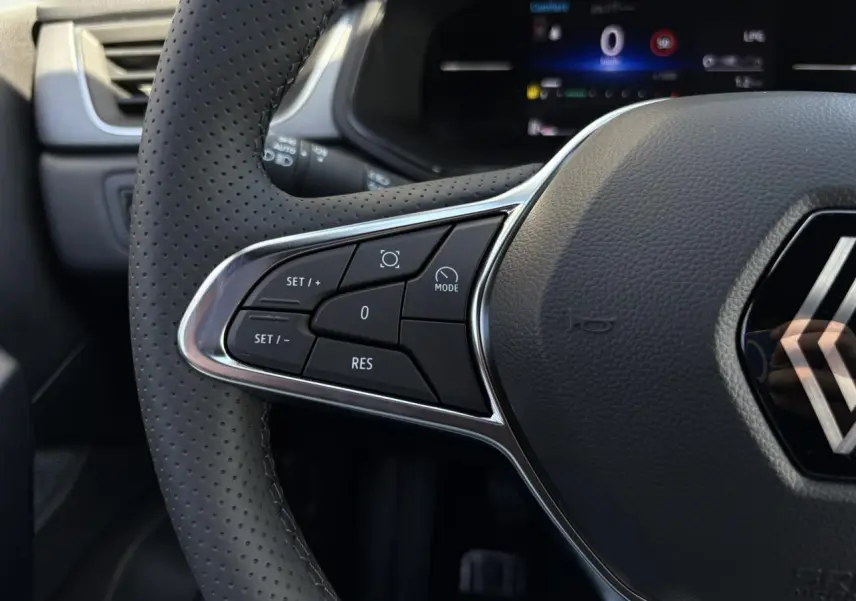 Gros plan sur le volant perforé du Renault Captur Gris Rafale 2025, avec commandes intégrées au côté gauche.