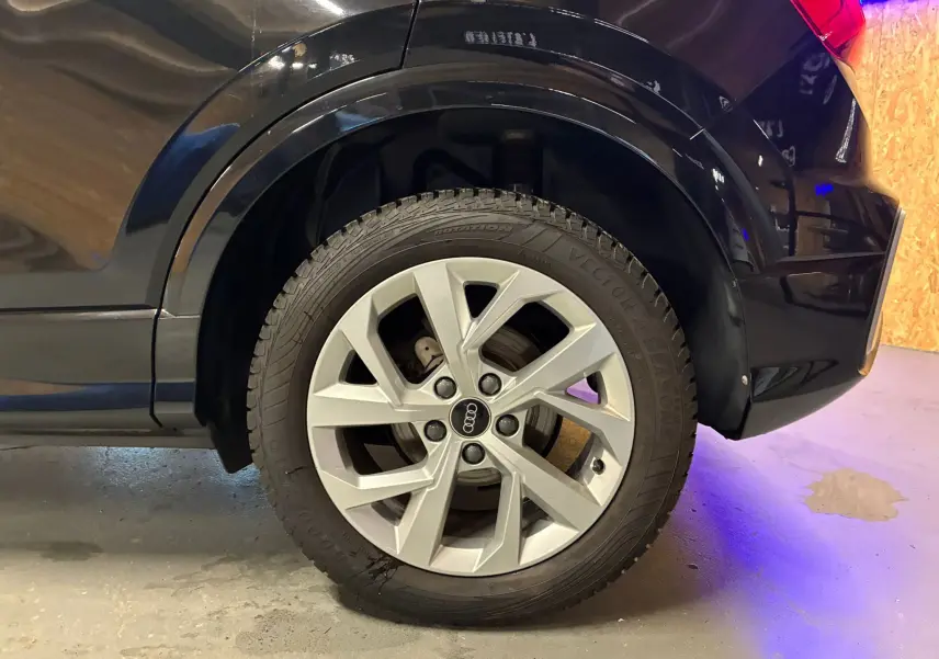 Gros plan sur la roue arrière droite d'un Audi Q2 noir 2023, mettant en valeur la jante argentée au design moderne.