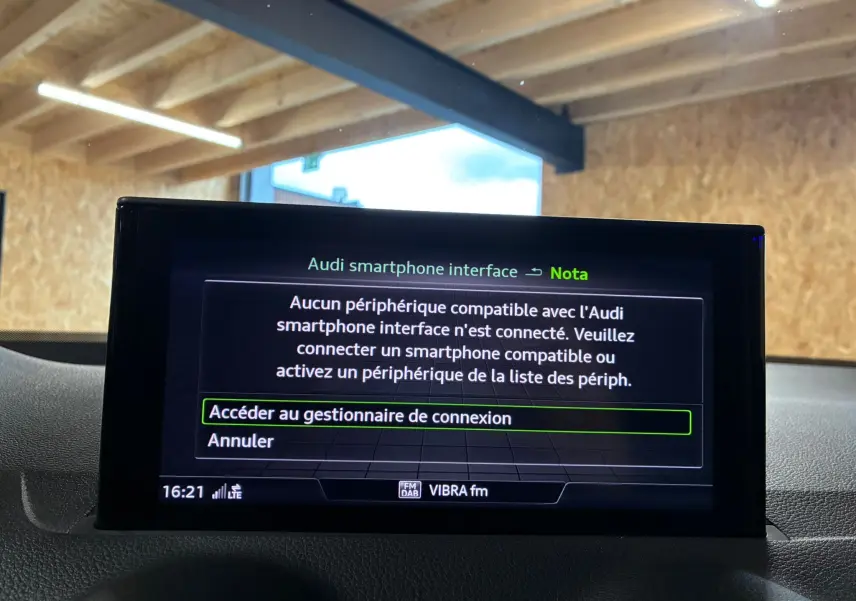 Écran central de l'Audi Q2 noir 2023 affichant le message de connexion smartphone dans un intérieur lumineux.