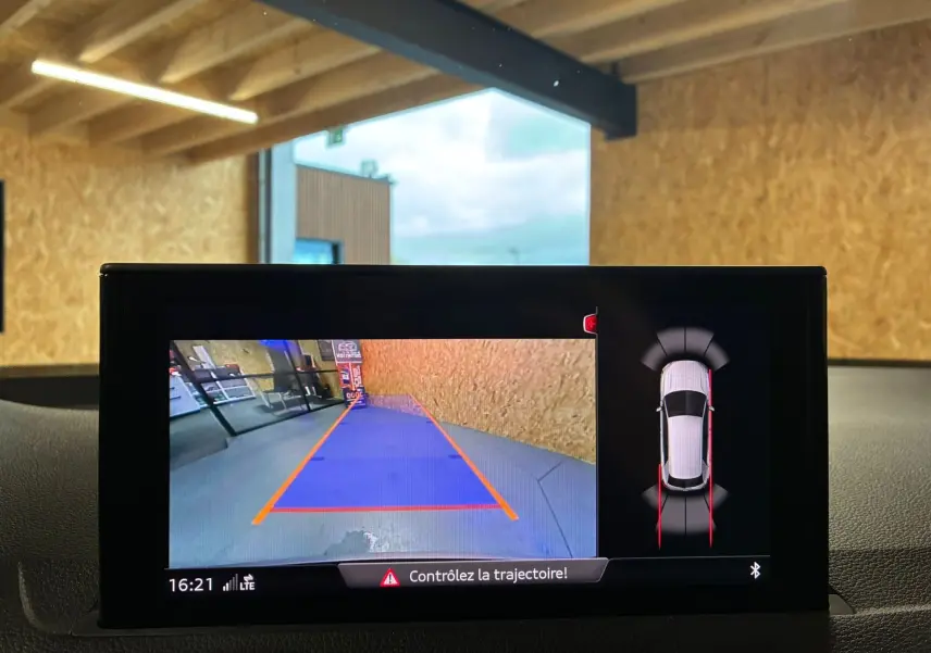 Écran de caméra de recul de l'Audi Q2 noir 2023 montrant la zone derrière avec guidage de trajectoire en bleu et orange.