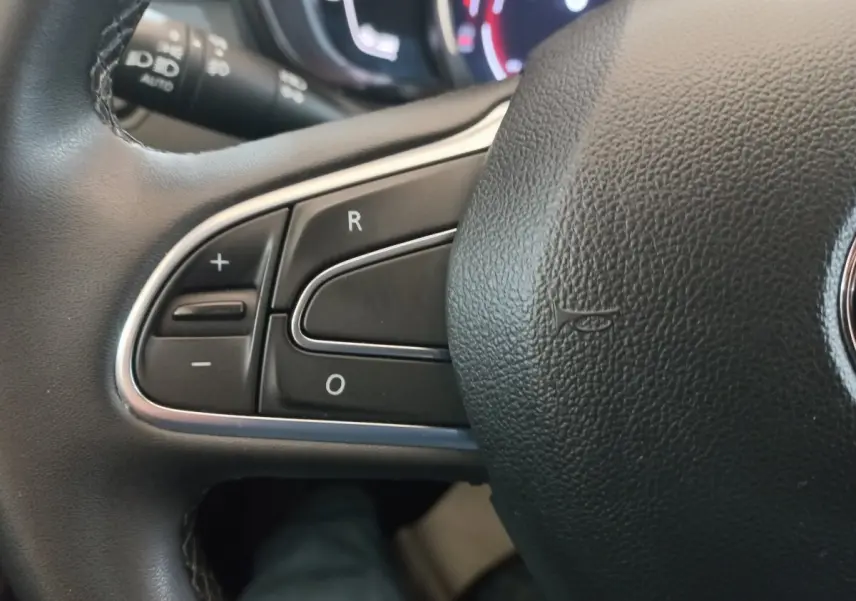 Gros plan sur les commandes de régulateur de vitesse au volant noir du Renault Kadjar Business gris foncé, 2022.