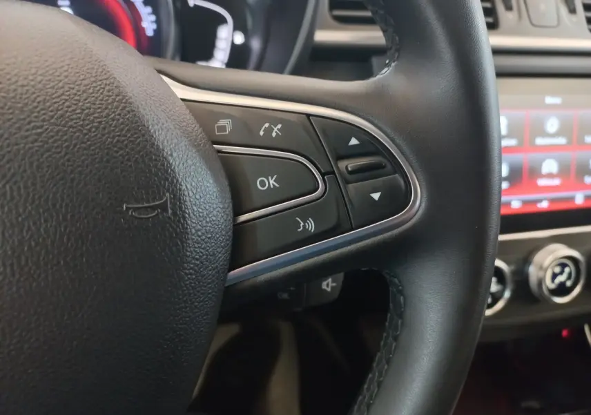 Gros plan sur la partie droite du volant noir du Renault Kadjar 2022 avec commandes vocales et écran tactile en arrière-plan.