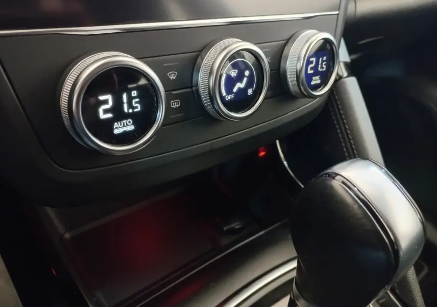 Gros plan sur la console centrale du Renault Kadjar gris foncé, montrant les commandes de climatisation digitales et le levier de vitesse automatique.