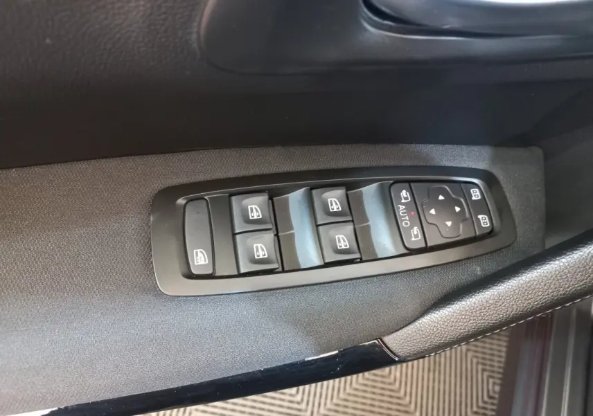 Gros plan sur les commandes électriques des vitres et rétroviseurs côté conducteur d’un Renault Kadjar gris foncé.