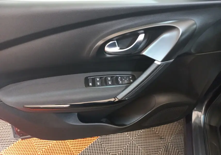 Vue rapprochée de la porte côté conducteur du Renault Kadjar gris foncé, avec commandes électriques des vitres et poignée argentée.
