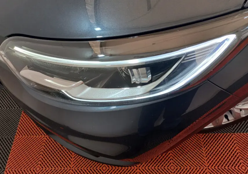 Gros plan sur le phare avant droit du Renault Kadjar gris foncé, mettant en valeur son design moderne et épuré.