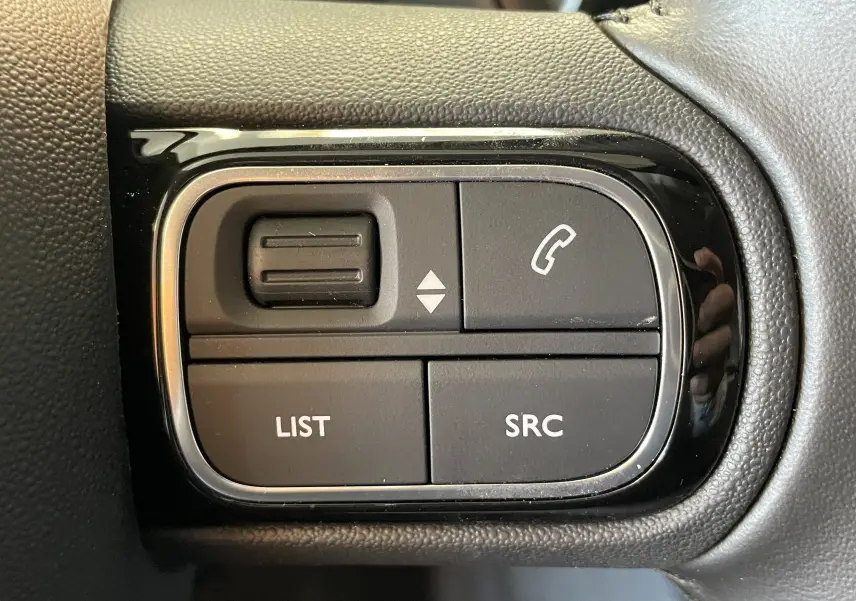 Gros plan sur les commandes au volant noir du Citroën C5 Aircross hybride 2025, boutons LIST, SRC et téléphone.