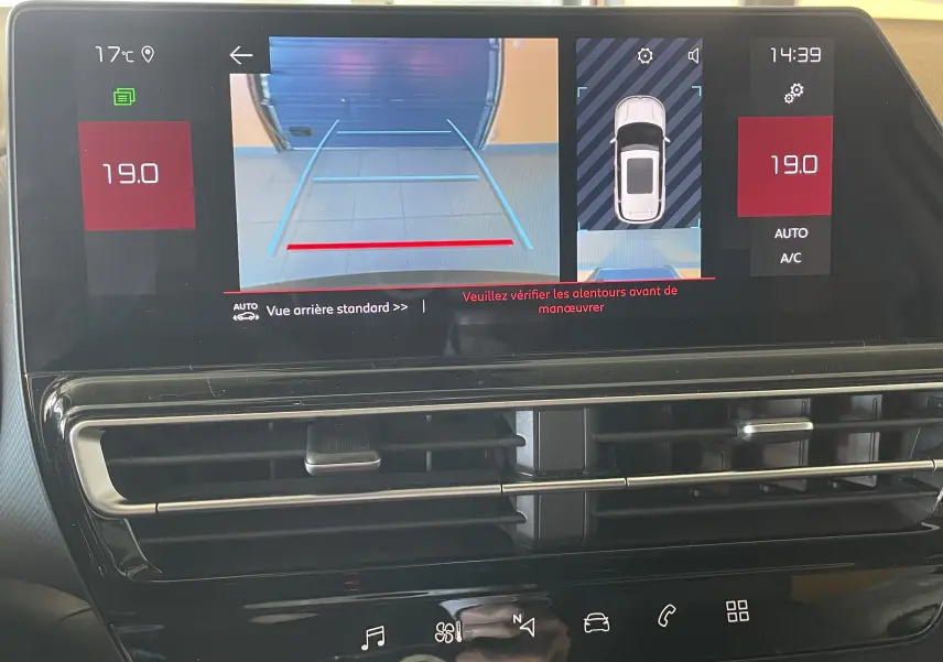Écran central du tableau de bord du Citroën C5 Aircross hybride 2025 montrant la caméra de recul et la climatisation automatique.