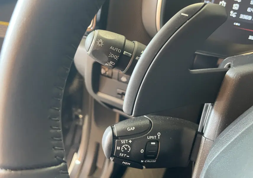 Gros plan sur les commandes au volant du Citroën C5 Aircross hybride gris platinium, avec régulateur de vitesse et éclairage automatique.