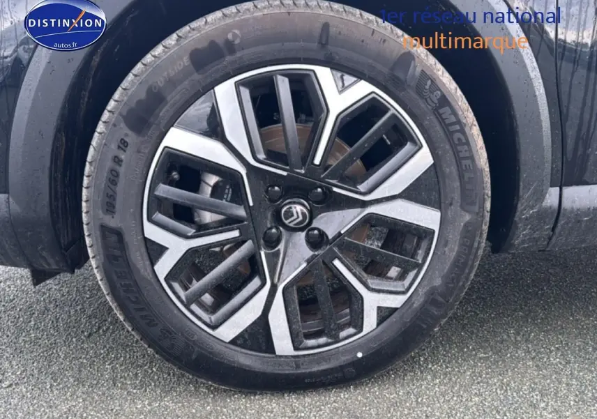 Gros plan sur la roue avant gauche noire de la Citroën C4 1.2 hybride 145 max automatique avec jante alu bicolore.