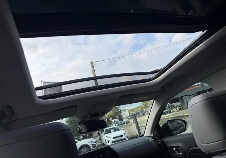 Vue intérieure du toit ouvrant panoramique du Citroën C5 Aircross noir métal 2024, avec ciel visible à travers le verre.