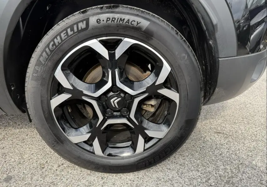 Gros plan sur la roue avant droite du Citroën C5 Aircross 2024 noir métal, jante alliage bicolore et pneu Michelin e-Primacy.