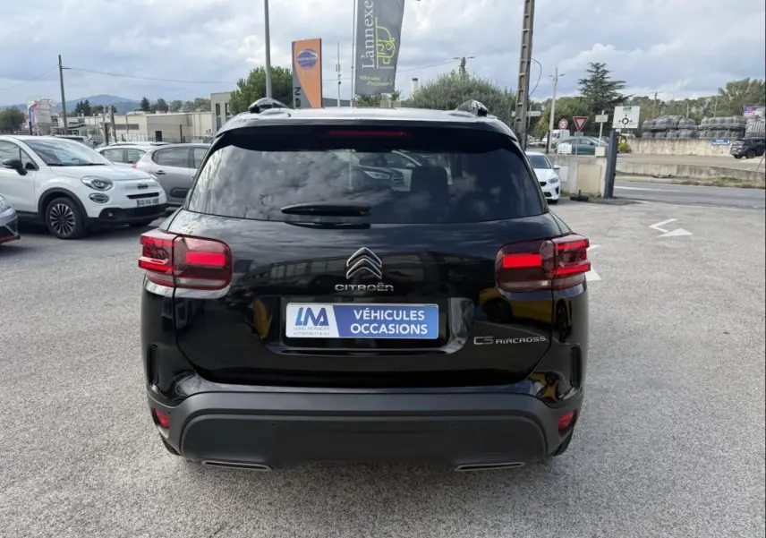 Vue arrière d'un Citroën C5 Aircross noir métal 2024 avec feux rouges et logo distinctif sur parking extérieur.