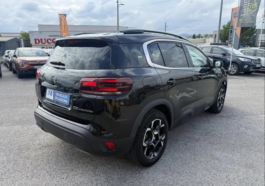 Vue 3/4 arrière droite d’un Citroën C5 Aircross noir métal 2024 avec jantes spécifiques et toit ouvrant visible.