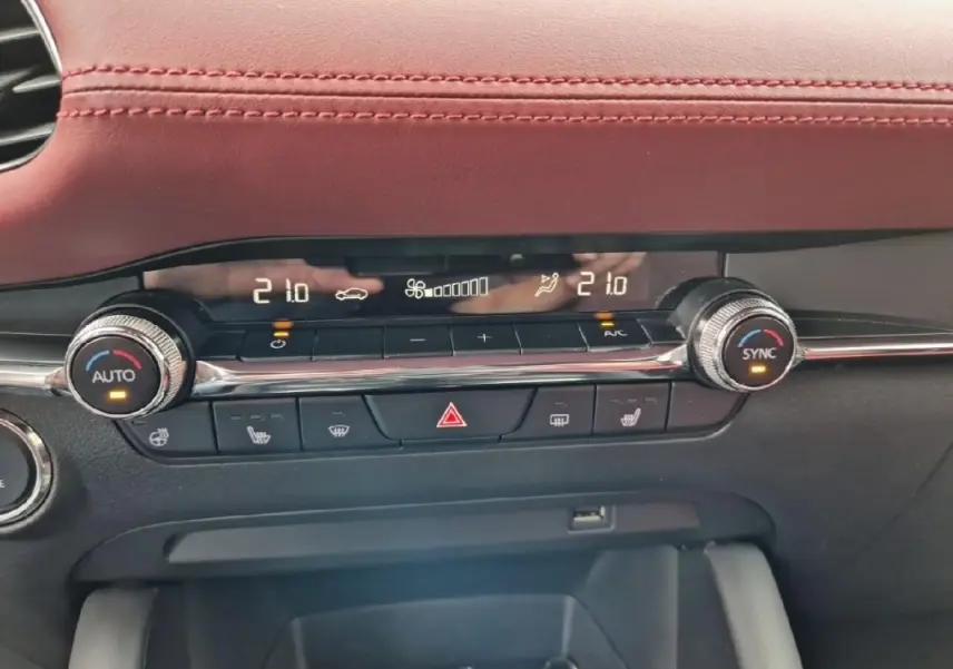 Vue rapprochée de la console centrale de la Mazda3 2020, mettant en valeur la climatisation digitale et le cuir rouge du tableau de bord.