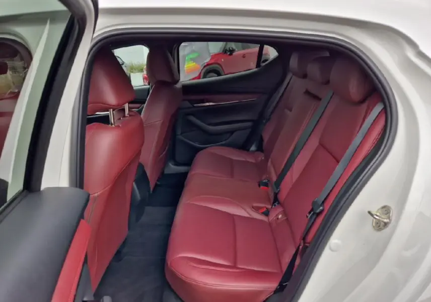 Vue intérieure côté droit montrant les sièges arrière en cuir rouge d'une Mazda3 blanche de 2020.