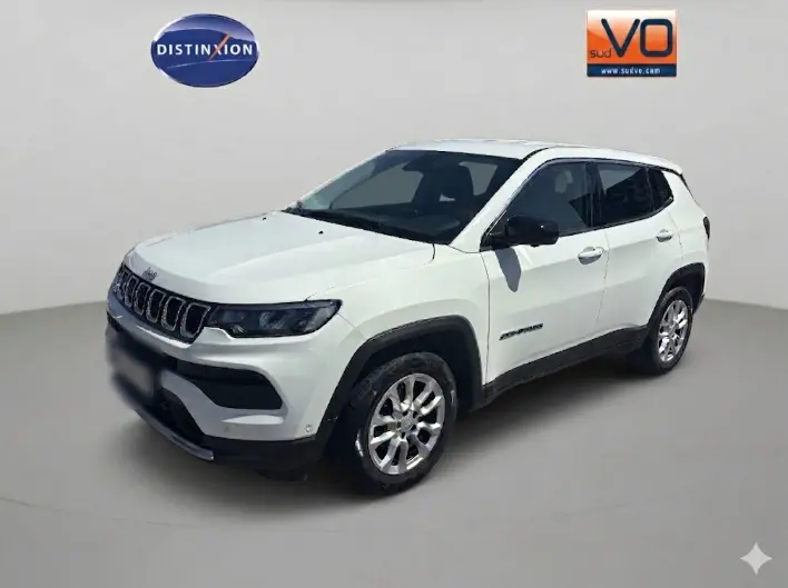 Jeep Compass blanc en 3/4 avant droit, avec calandre distinctive et jantes argentées visibles.