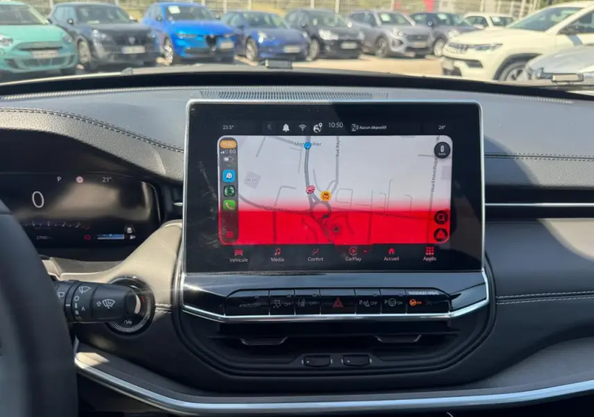 Vue intérieure centrée sur l'écran tactile du tableau de bord du Jeep Compass blanc 2025, avec commandes visibles.