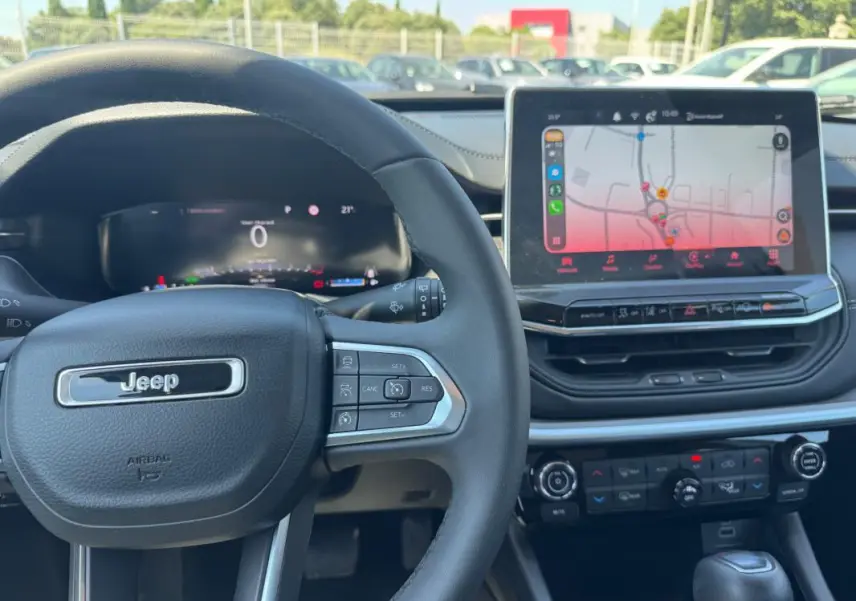 Vue intérieure centrée sur le volant Jeep et l’écran tactile du tableau de bord du Compass blanc 2025.