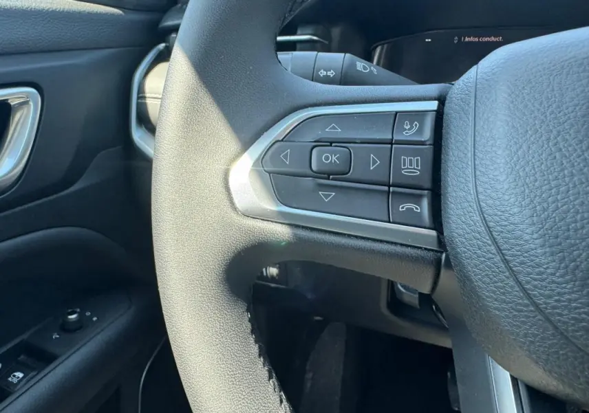 Gros plan sur le volant noir de la Jeep Compass 2025 avec commandes multifonctions côté gauche et tableau de bord partiel.