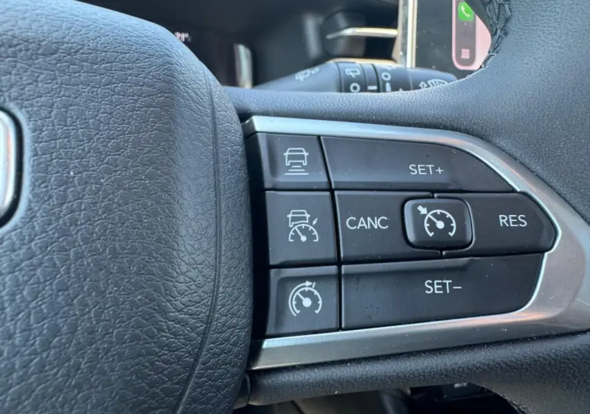 Gros plan sur les commandes du régulateur de vitesse au volant d’un Jeep Compass blanc 2025.