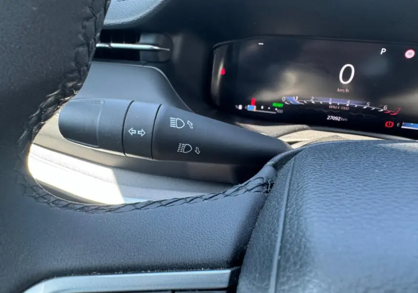 Gros plan sur la manette de clignotants et le tableau de bord numérique noir du Jeep Compass blanc 2025.