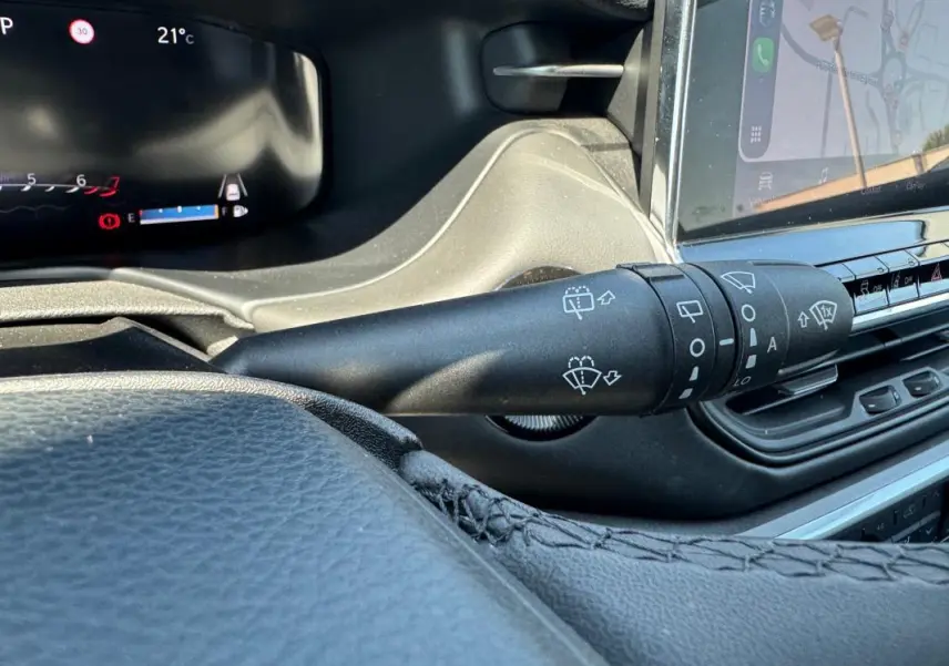 Gros plan sur la commande d’essuie-glace du tableau de bord noir du Jeep Compass blanc 2025, avec écran tactile visible.