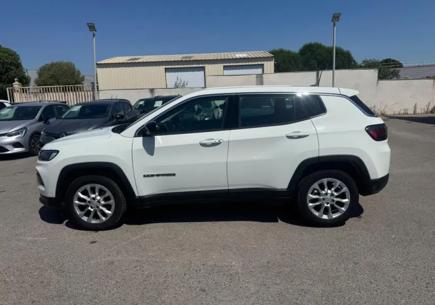 Vue de profil côté gauche d'un Jeep Compass blanc 2025 avec jantes alliage et vitres teintées.