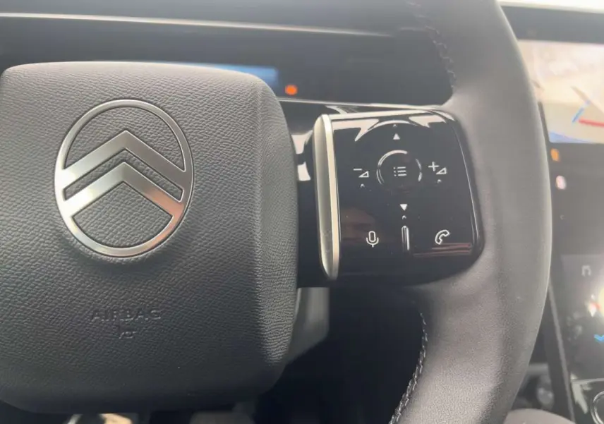 Gros plan sur le volant cuir multifonctions du Citroën C5 Aircross Hybrid 145 Plus, avec logo chrome et commandes tactiles.