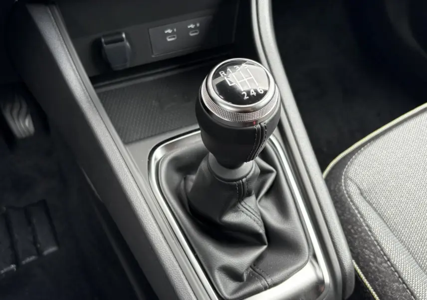 Le levier de vitesse manuel noir de la Renault Captur 2025 avec coutures visibles et console centrale grise.