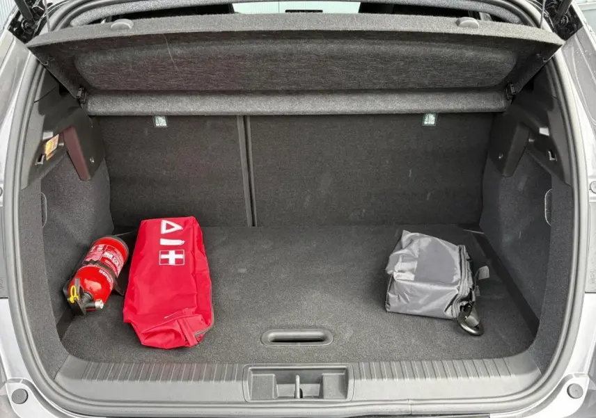 Coffre ouvert d'un Renault Captur Gris Cassiopée 2025, avec trousse de secours rouge et extincteur visibles.