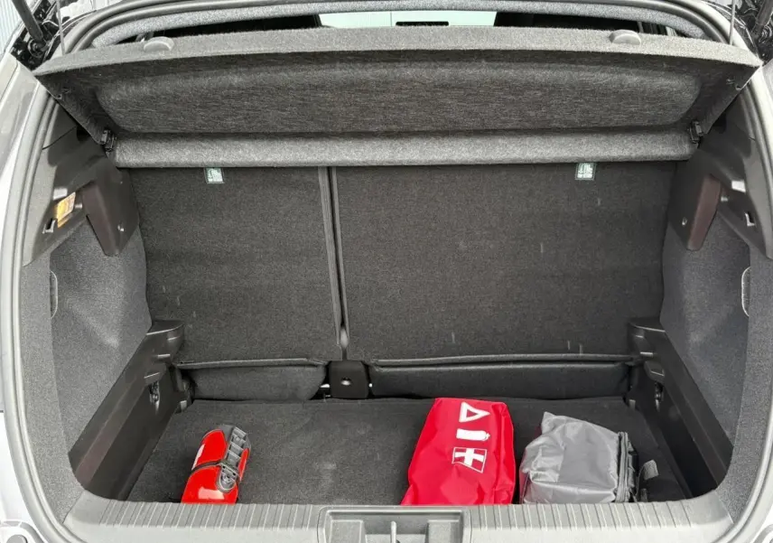 Coffre ouvert d'un Renault Captur Gris Cassiopée 2025, vue arrière montrant un kit de sécurité rouge et un sac gris.