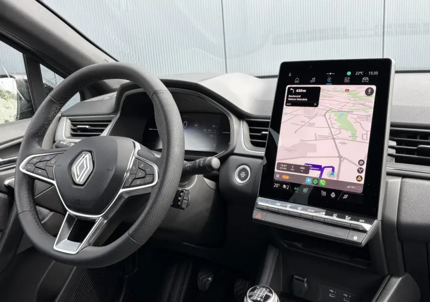 Intérieur du Renault Captur 2025 vu côté conducteur, volant multifonction et écran tactile vertical avec navigation affichée.