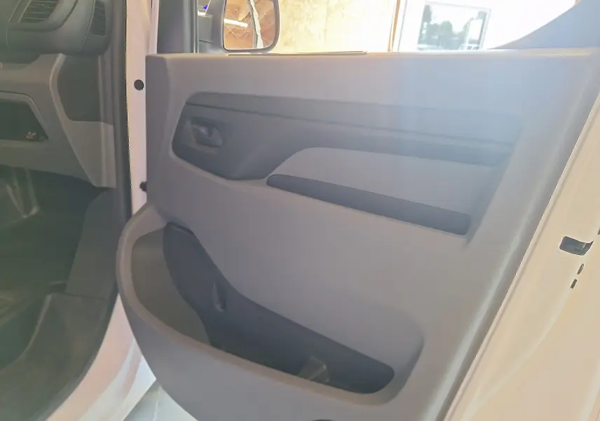 Intérieur de la porte avant gauche d'un Citroën Jumpy blanc 2020, mettant en valeur la poignée et le rangement intégré.