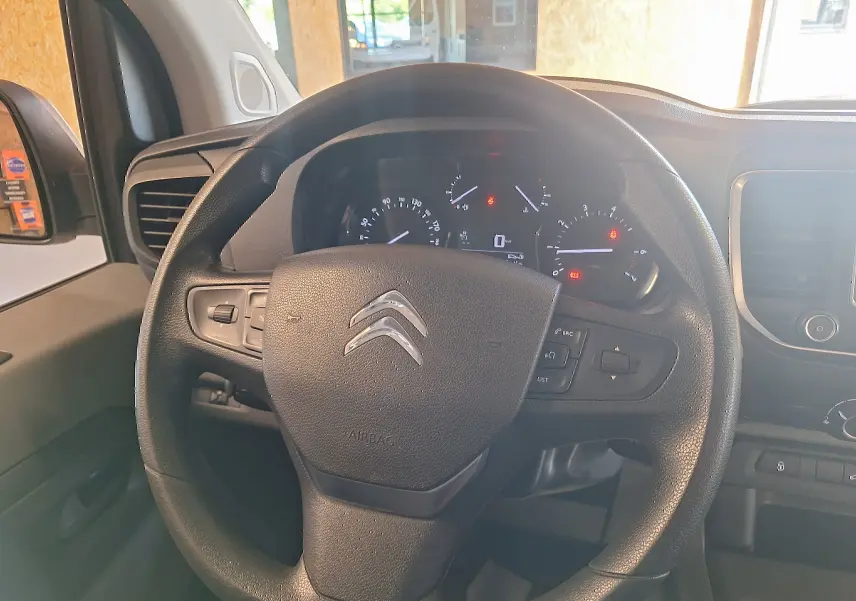 Vue rapprochée du volant noir de la Citroën Jumpy 2.0 BlueHDi 120 Club 2020 avec tableau de bord et commandes visibles.