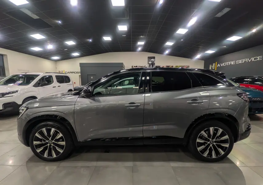 Renault Austral 2024 gris schiste avec toit noir, vue de profil côté gauche, jantes alliage bicolores visibles.