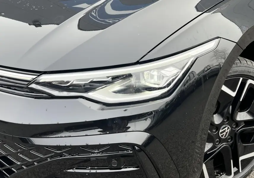 Gros plan sur l'avant droit noir brillant d'une Volkswagen Golf VIII R-Line avec phare LED et jante alliage 18 pouces.