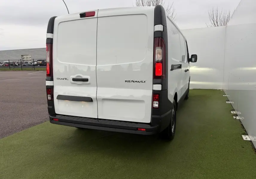 Vue arrière d’un Renault Trafic Fourgon blanc glacier, portes arrière tôlées ouvertes à 180°, feux verticaux rouges et blancs.