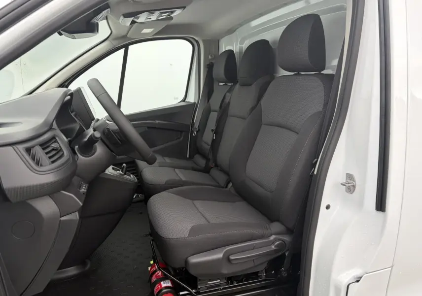 Vue intérieure côté conducteur du Renault Trafic Fourgon blanc glacier, montrant la banquette passager trois places en tissu gris.