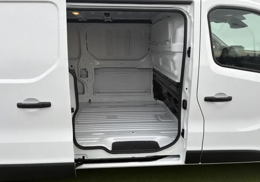 Vue latérale droite sur l’espace de chargement blanc glacier ouvert du Renault Trafic Fourgon 2025, intérieur tôlé vide.