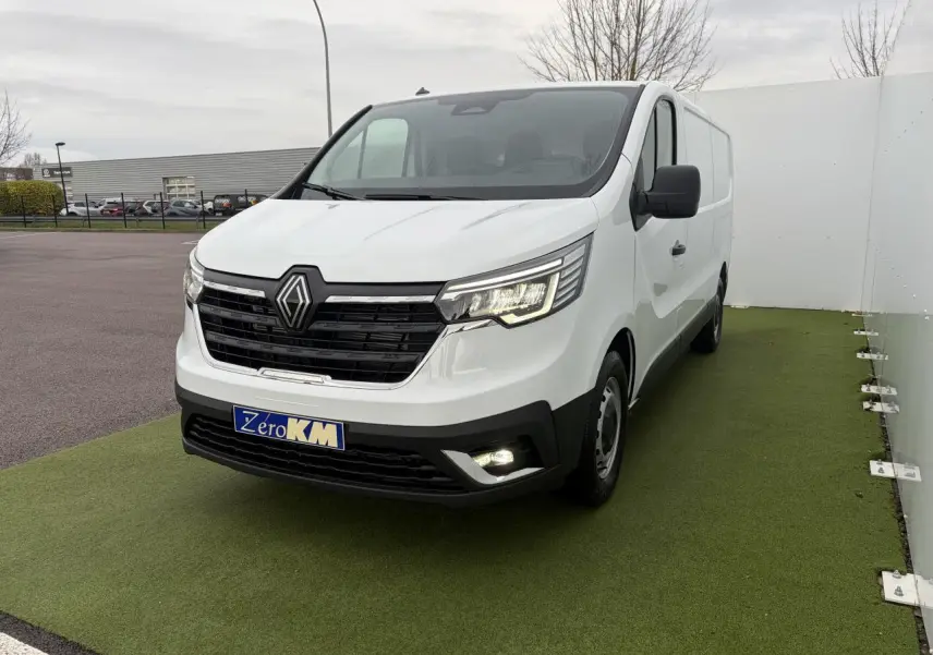 Renault Trafic Fourgon blanc glacier vu en 3/4 avant droit, avec projecteurs LED et calandre noire brillante.