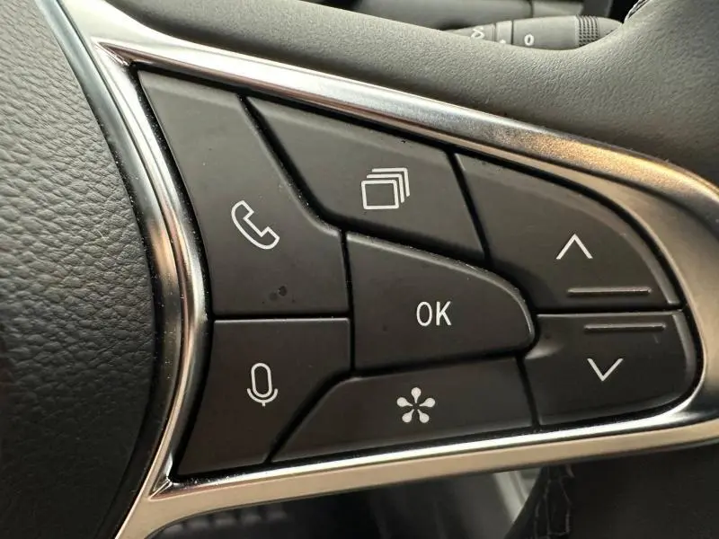 Gros plan sur les commandes multifonctions au volant du Renault Captur 2025, boutons noirs avec cadre chromé.